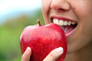 Person beißt in einen roten Apfel