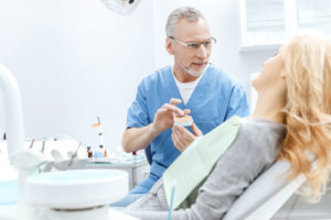 Zahnarzt zeigt Patientin einen Gebissabdruck